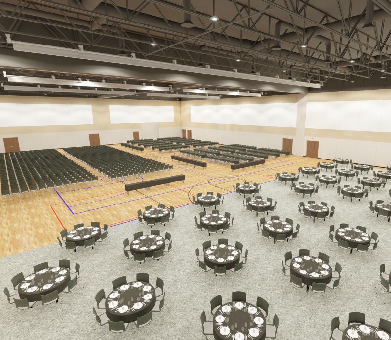 Series of black, circular tables and chairs in large room arranged in rows in large room with cutlery on top of tables at The Box Event Center in Box Elder, SD